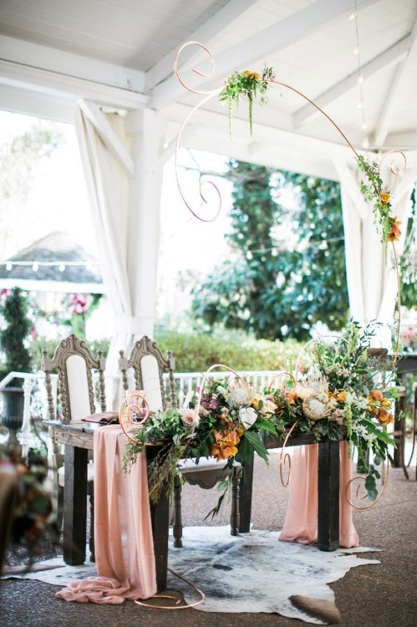Our florist created a custom copper sculpture draped with flowers to frame this stunning sweetheart table design at a recent event at CJ's Off the Square