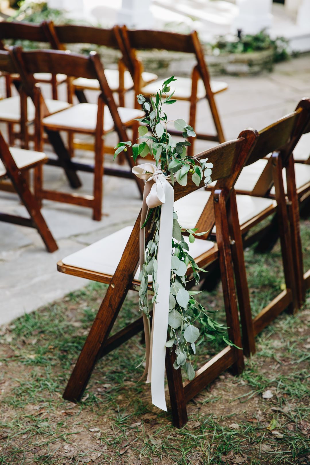 Eucalyptus accents on wedding ceremony chairs for earthy summer garden wedding in September, neutrals & greenery