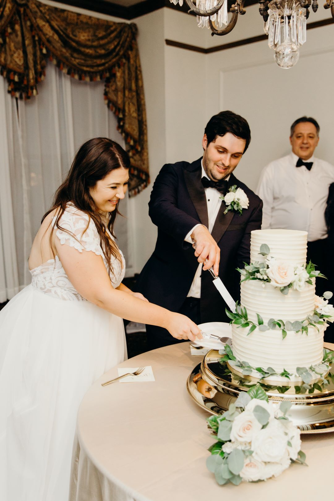 Bride and groom cutting the cake at their earthy summer garden wedding in September, neutrals & greenery