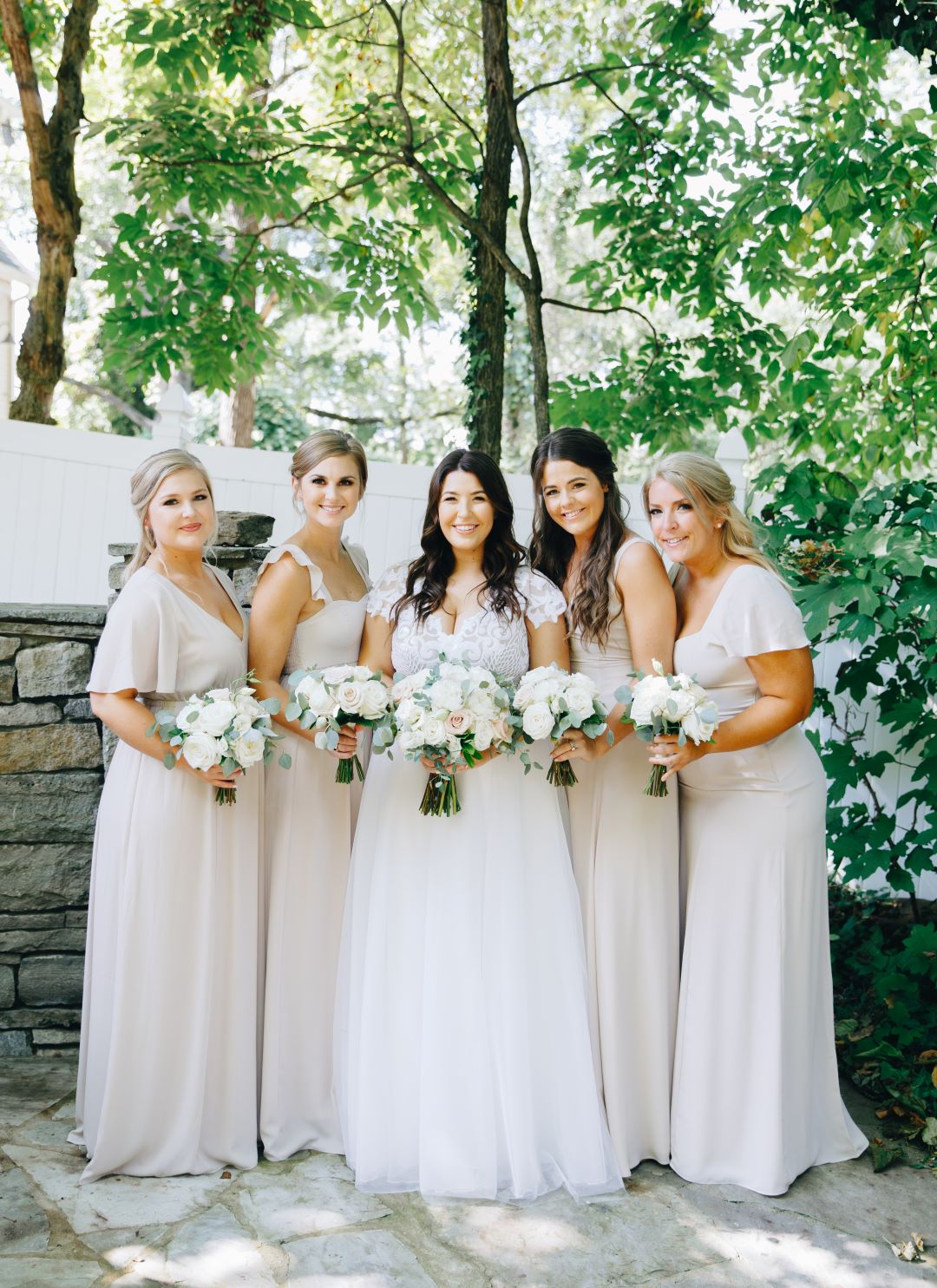 Bridal party in mismatched neutral gown styles with rose bouquets earthy summer garden wedding in September, neutrals & greenery