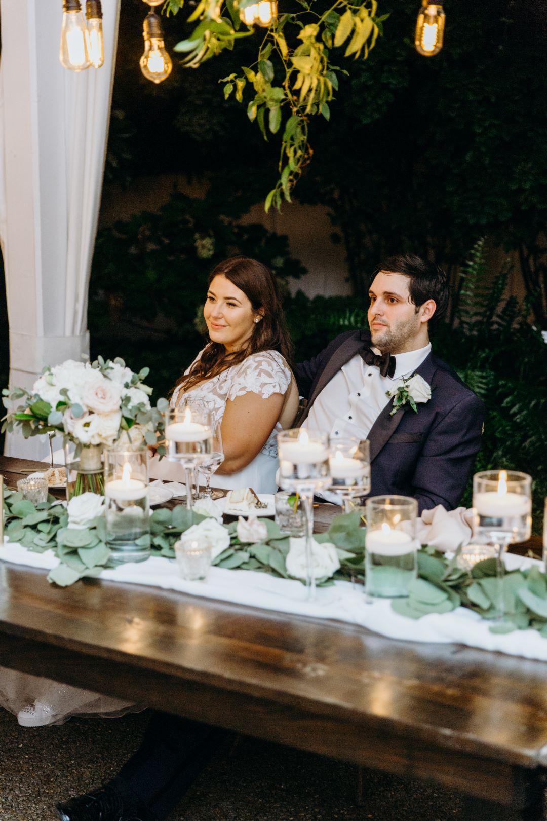 Bride and groom sitting at head table during their reception at earthy summer garden wedding in September, neutrals & greenery