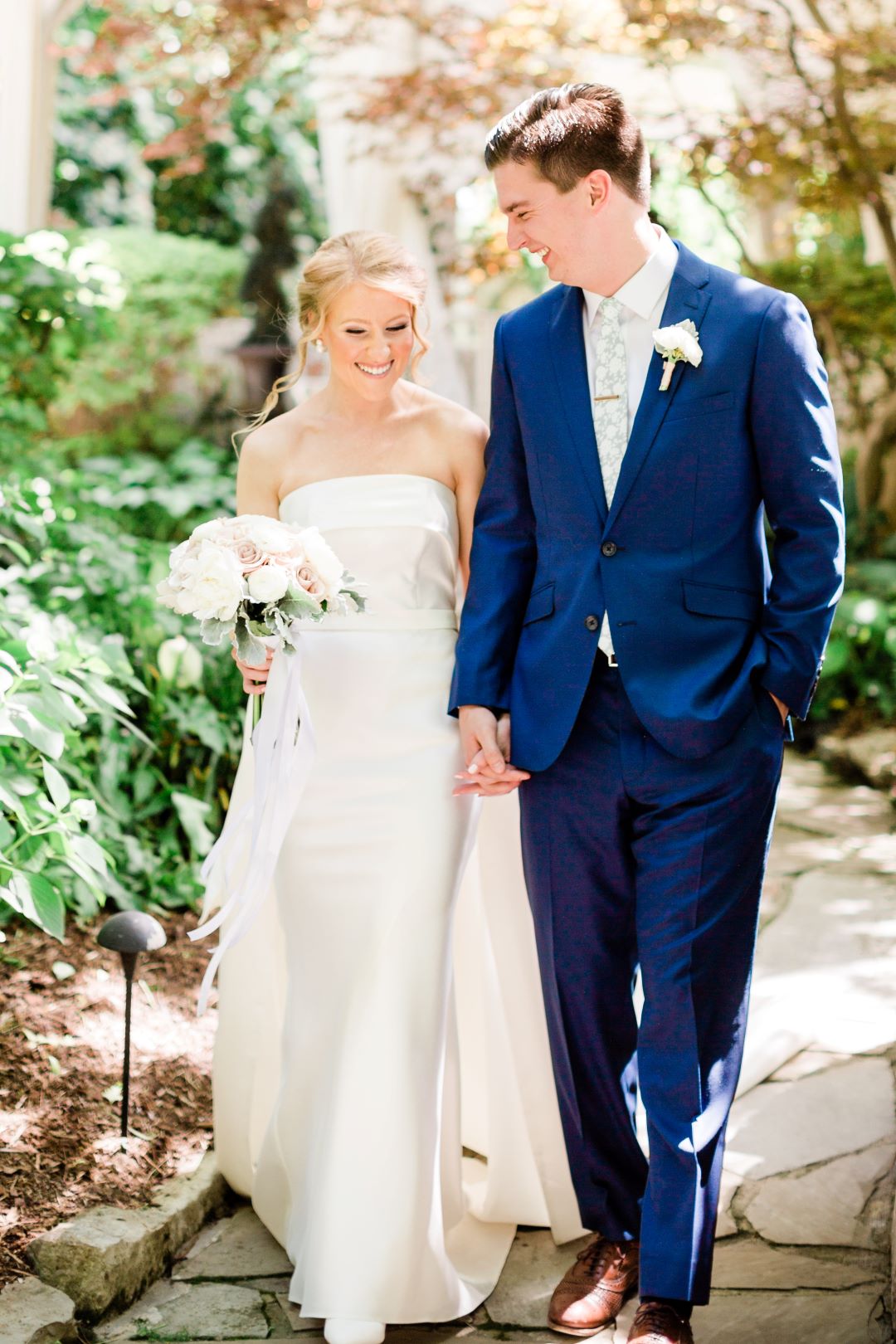 CJ's Off The Square | Bride and groom holding hands walking through the wedding venue's garden
