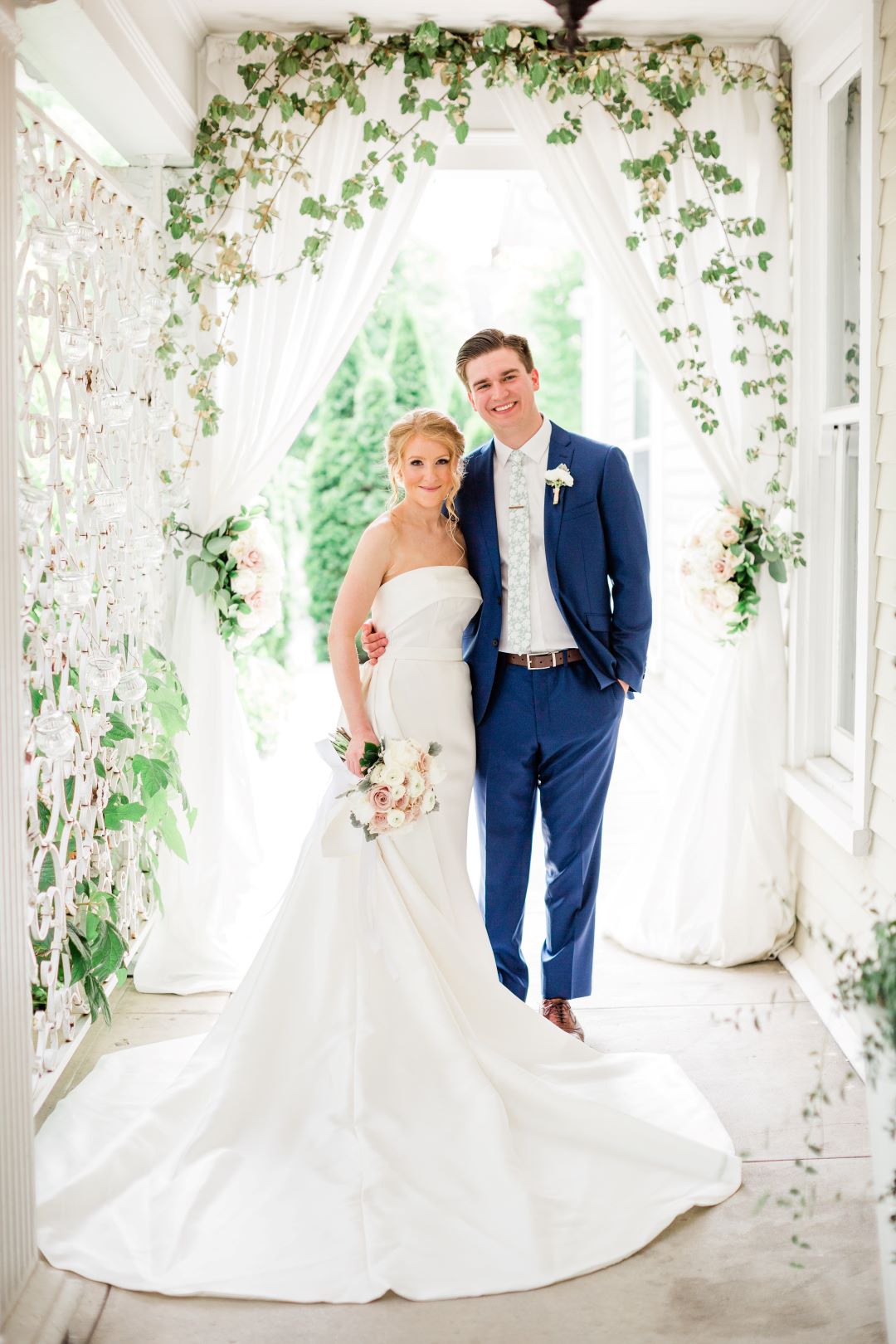 CJ's Off The Square | Bride and groom standing under an archway of greenery next to trellis