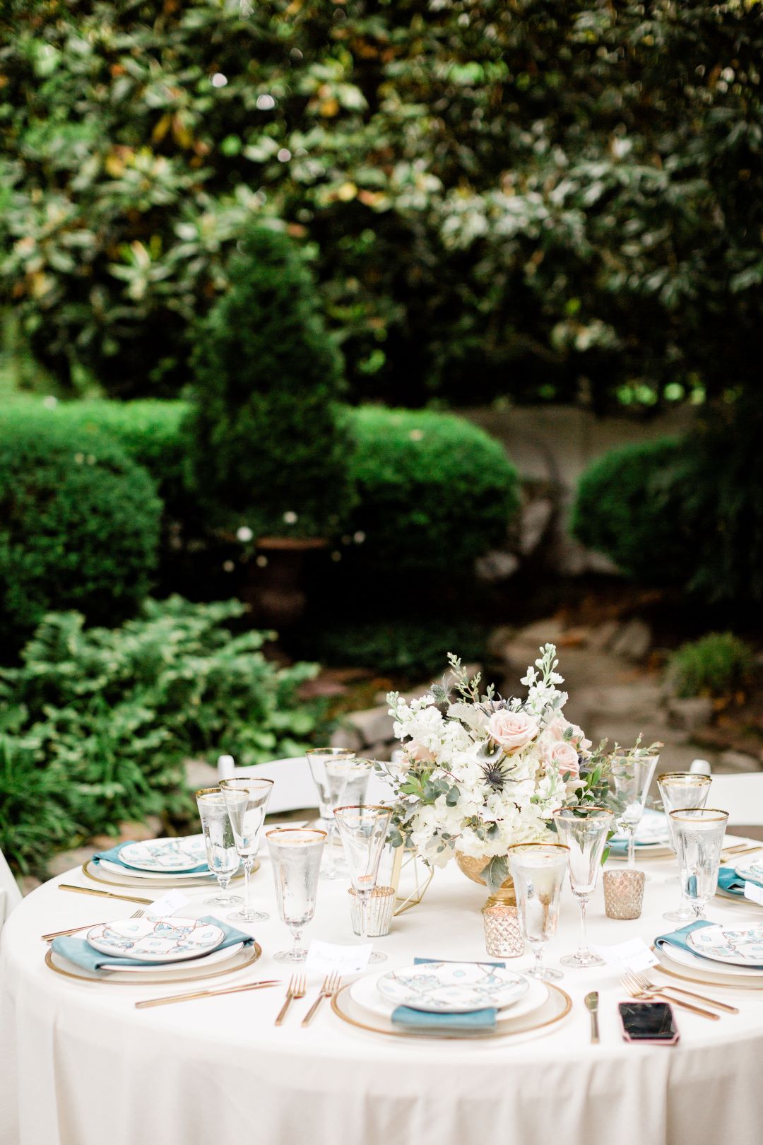 CJ's Off The Square | Stunning table settings in the garden surrounded by lush green trees and shrubs