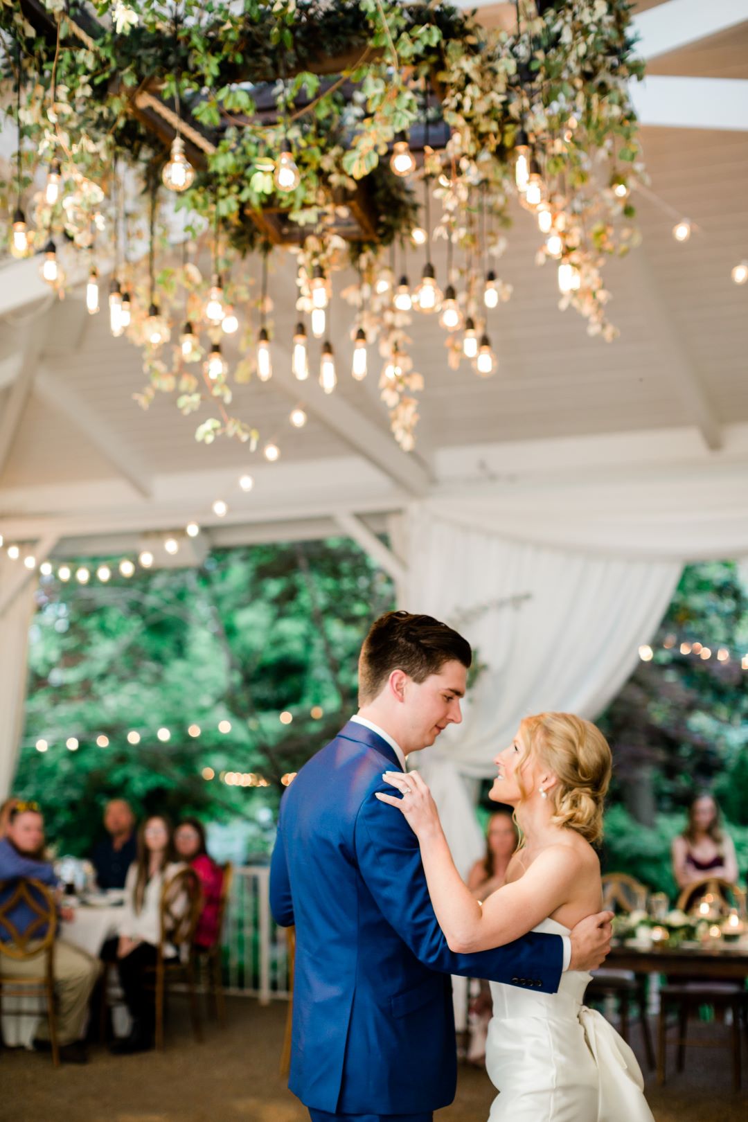 CJ's Off The Square | Bride and groom's first dance under the giant leafy chandelier with edison bulbs