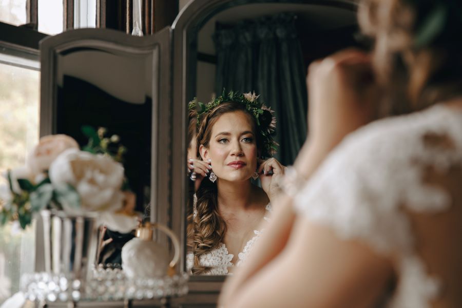 Bride putting on her earrings in the mirror before wedding / earthy / fall / October / burgundy