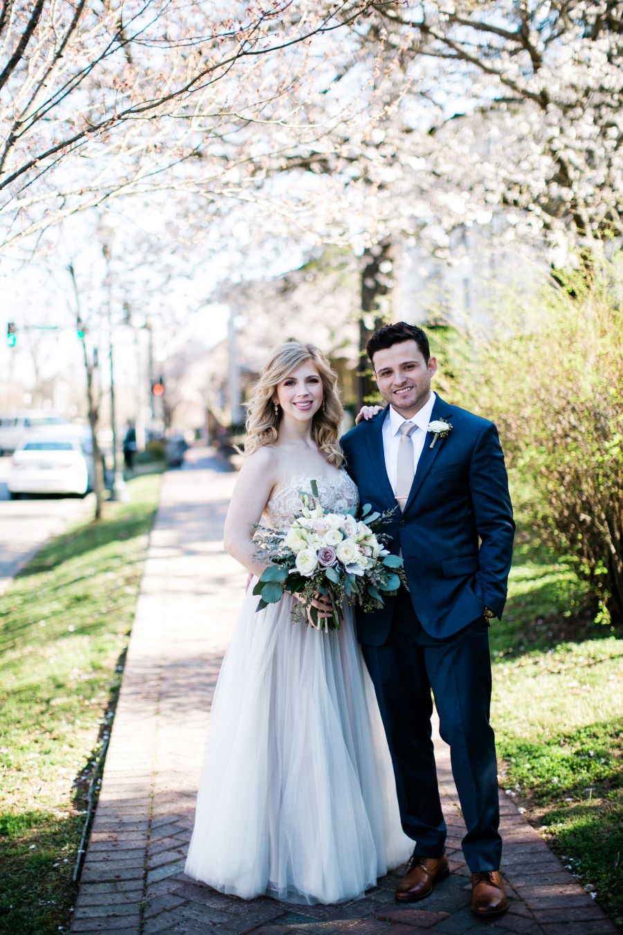 Bride and groom posing on brick sidewalk in front of wedding venue / Elopement / Spring / March / Dusty Rose
