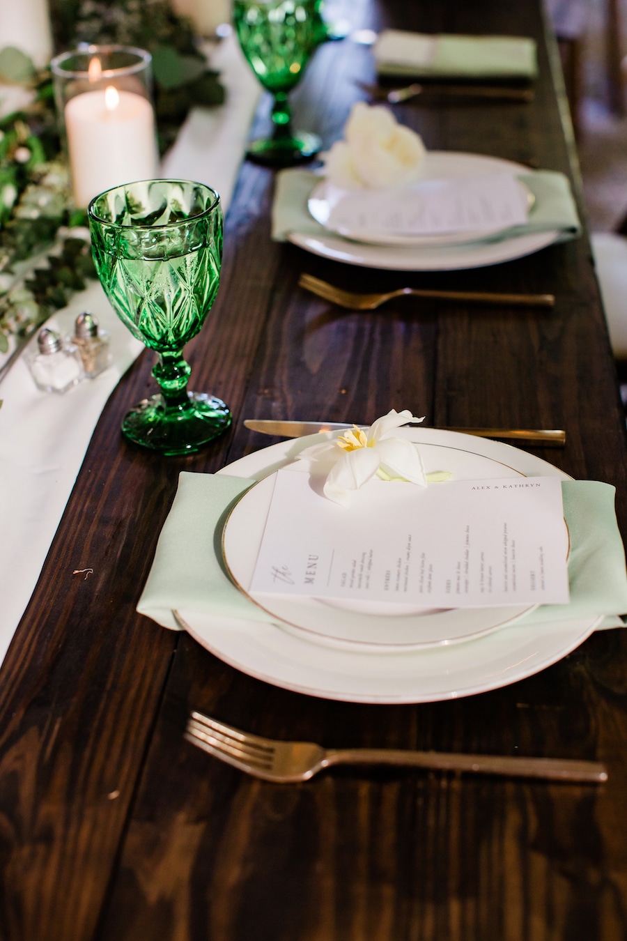 Farm table with white runner, greenery and candles in neutral wedding colors at Nashville wedding venue CJ’s Off the Square.
