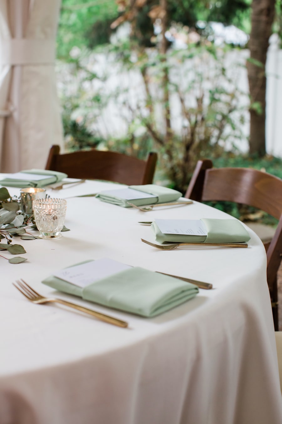 Farm table with white runner, greenery and candles in neutral wedding colors at Nashville wedding venue CJ’s Off the Square.
