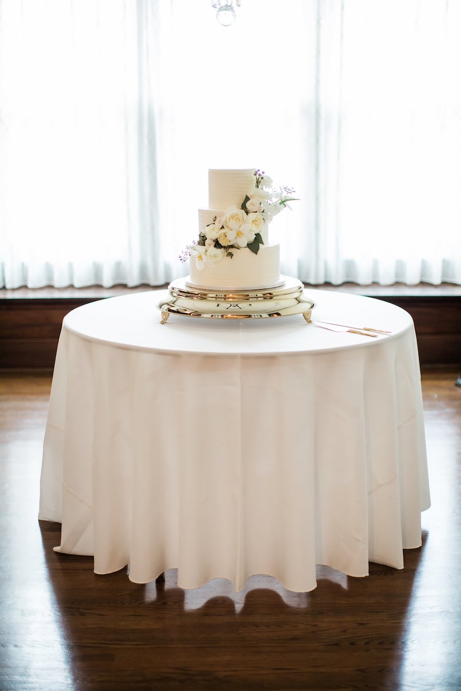 Simple but elegant wedding cake with buttercream icing and fresh flowers and greenery at garden wedding venue CJ’s Off the Square near Nashville, TN.