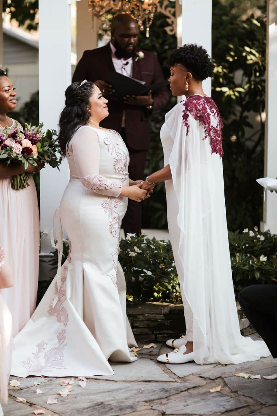 Two brides holding hands at the altar during garden wedding ceremony / romantic lgbtq / fall / September / blush / burgundy