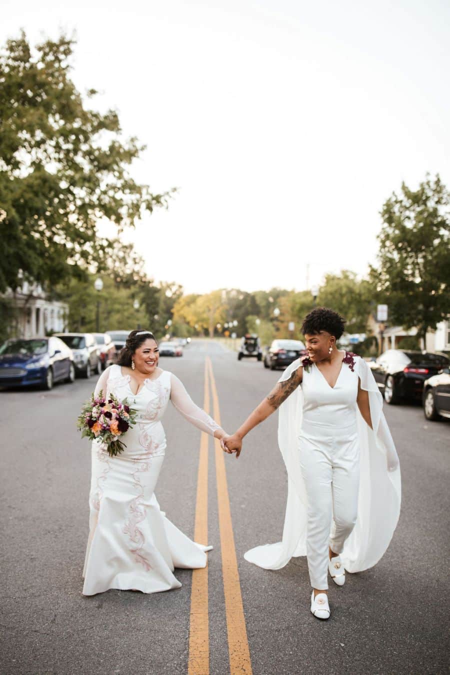 Brides holding hands in the middle of the street after being married / romantic lgbtq / fall / September / blush / burgundy