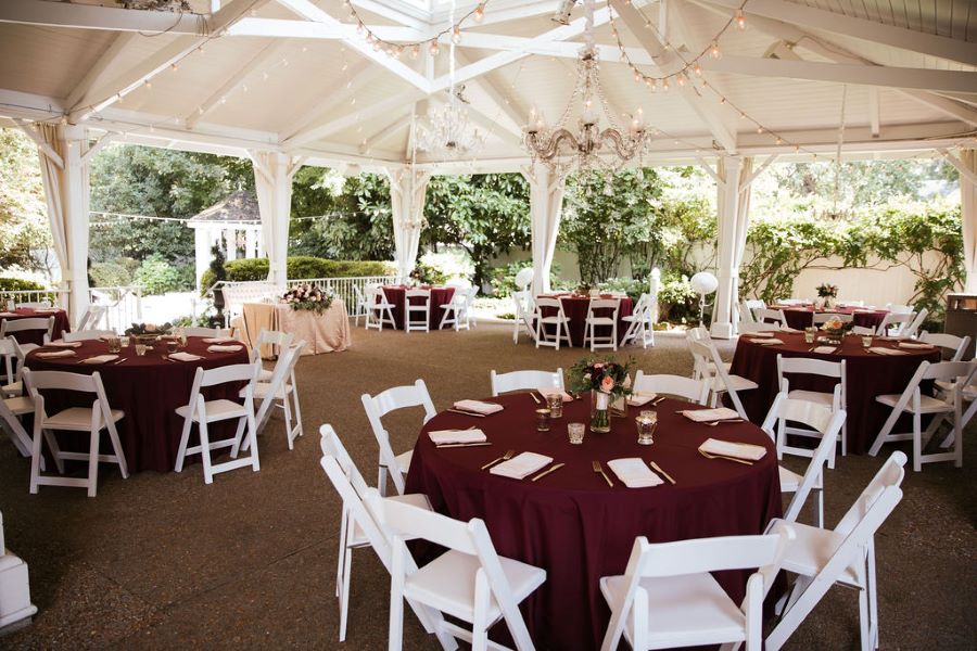 Burgundy linens on round tables with white chairs for outdoor garden wedding reception / romantic lgbtq / fall / September / blush / burgundy