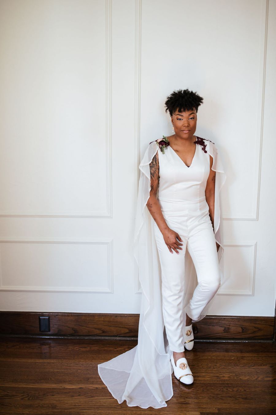 Bride posing in her white pant suit and cape before ceremony / romantic lgbtq / fall / September / blush / burgundy