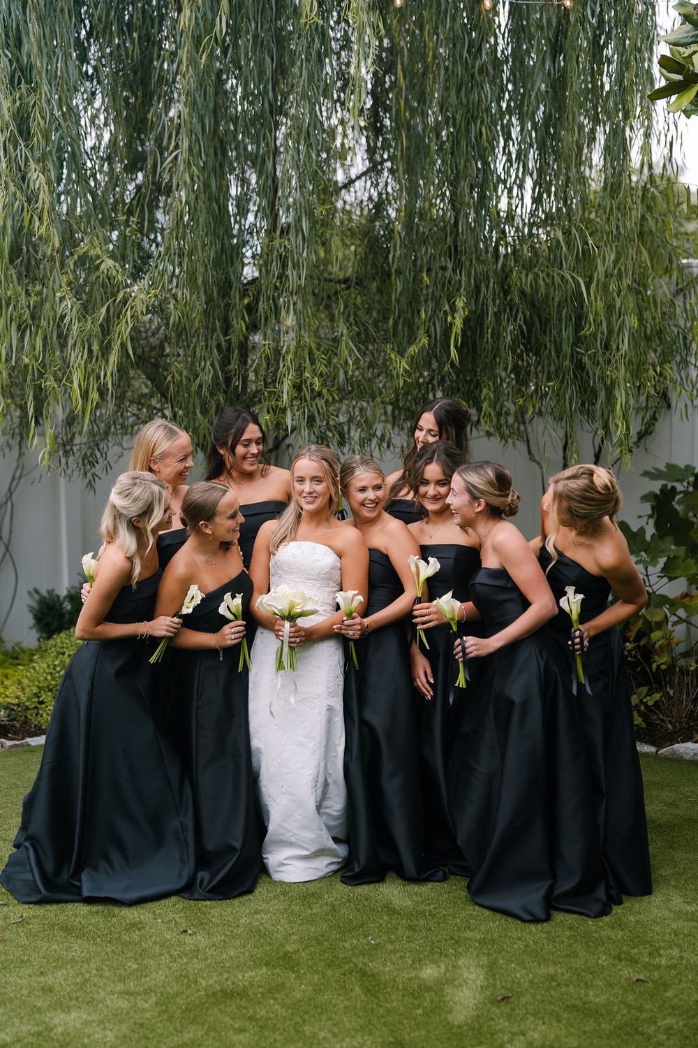 Bridesmaids in classic black dresses in the garden at CJ's Off the Square