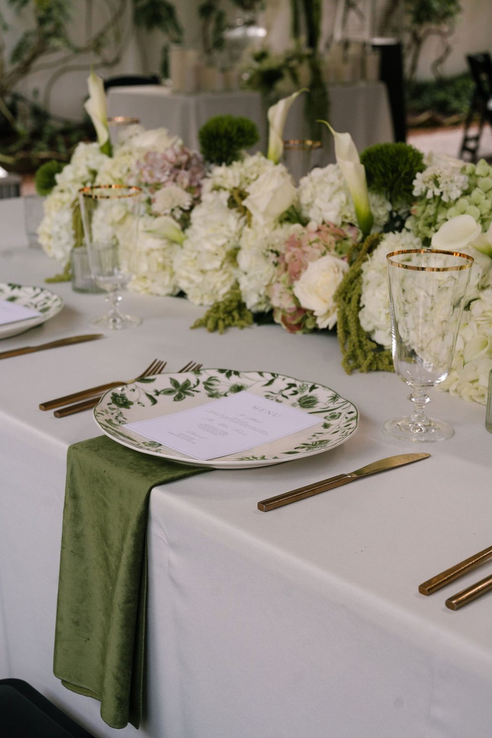 Fern green velvet napkin with patterned china and gold flatware