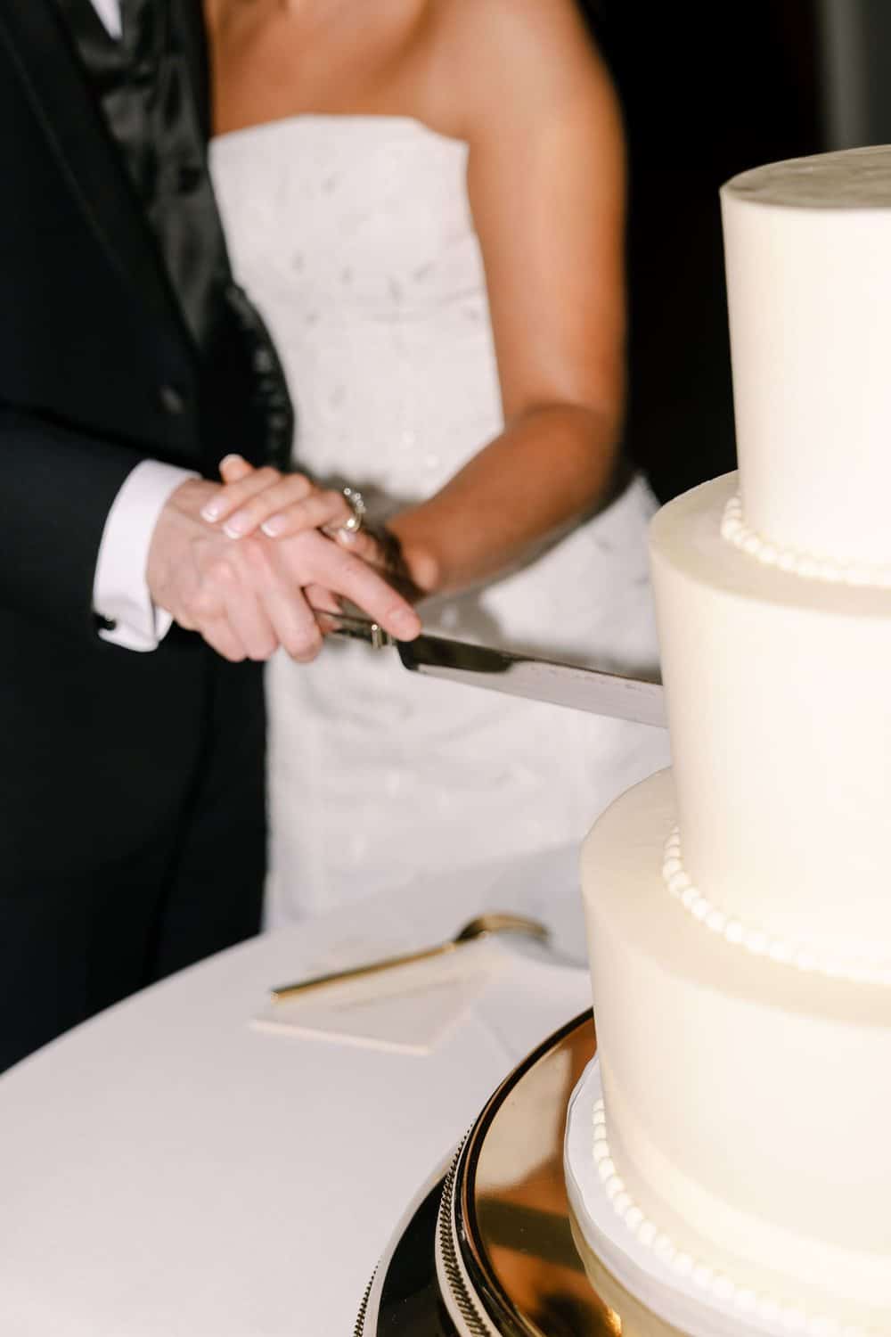 Addison and Caleb cutting their custom three tier white wedding cake