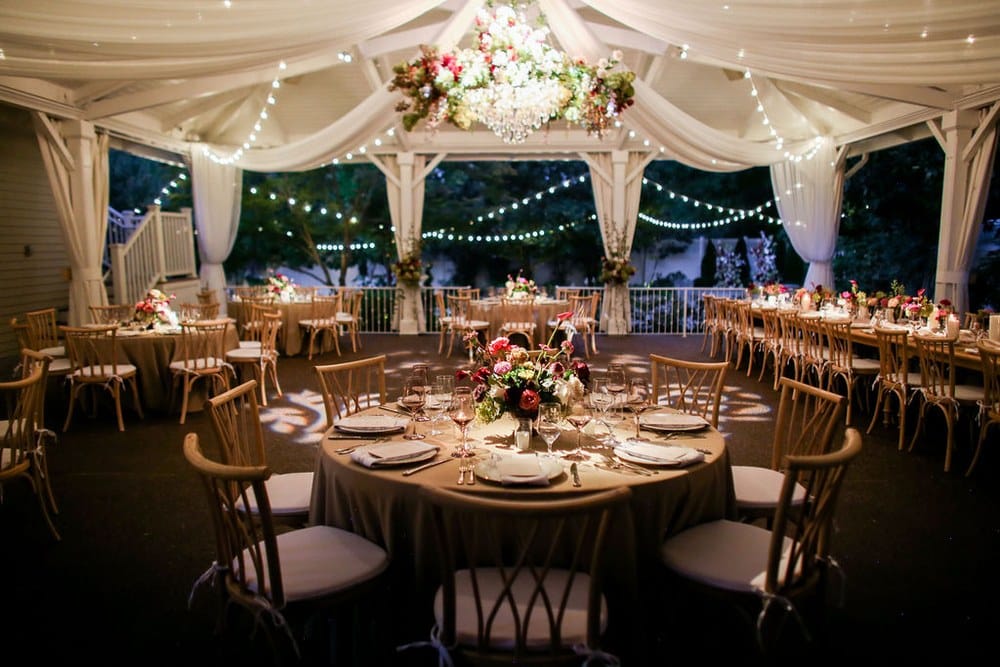 Evening wedding reception in the covered pavilion with chandeliers and string lights at CJ's Off the Square
