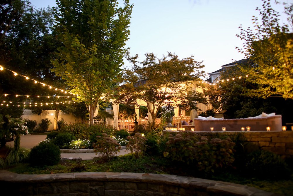 Garden with string lights and the warmly lit wedding pavilion at dusk in Franklin Tennessee