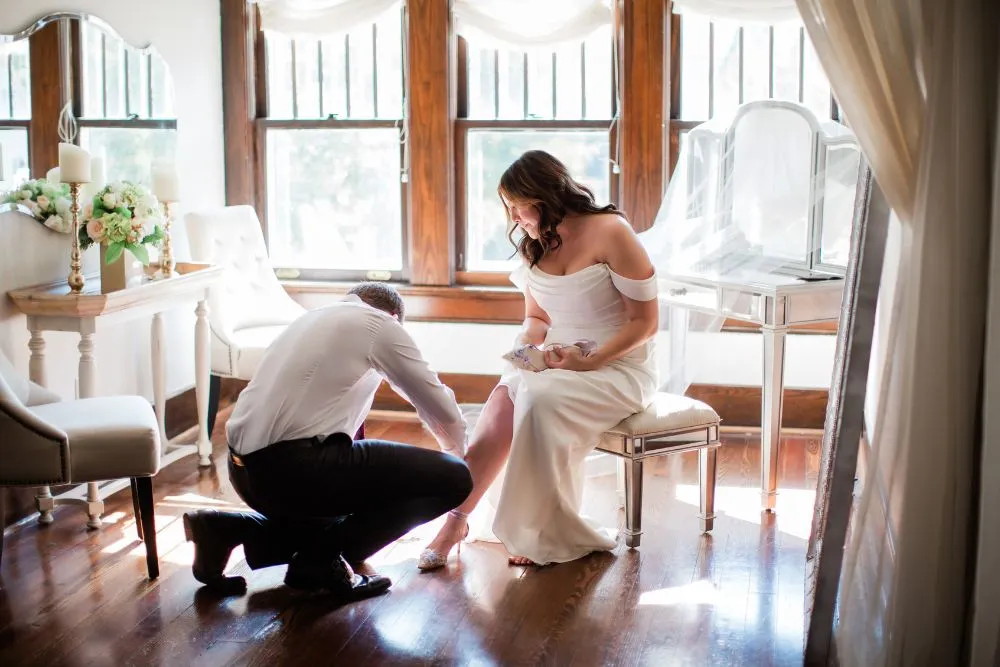 groom buckles his brides shoe in the bridal suite at cjs off the square in Franklin tn